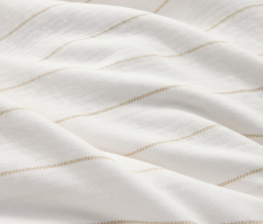Gros plan d'un tissu blanc froissé avec de fines rayures horizontales marron clair.