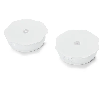 Deux lumières rondes blanches de palet reposent sur une surface blanche.