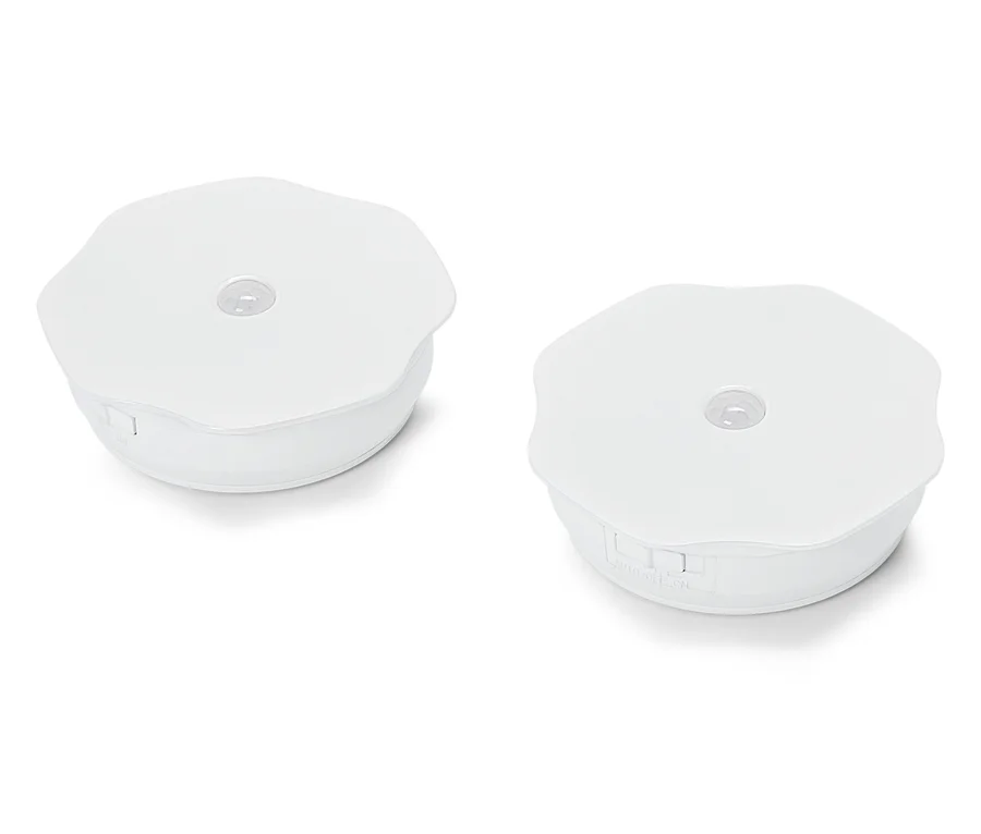 Deux lumières rondes blanches de palet reposent sur une surface blanche.