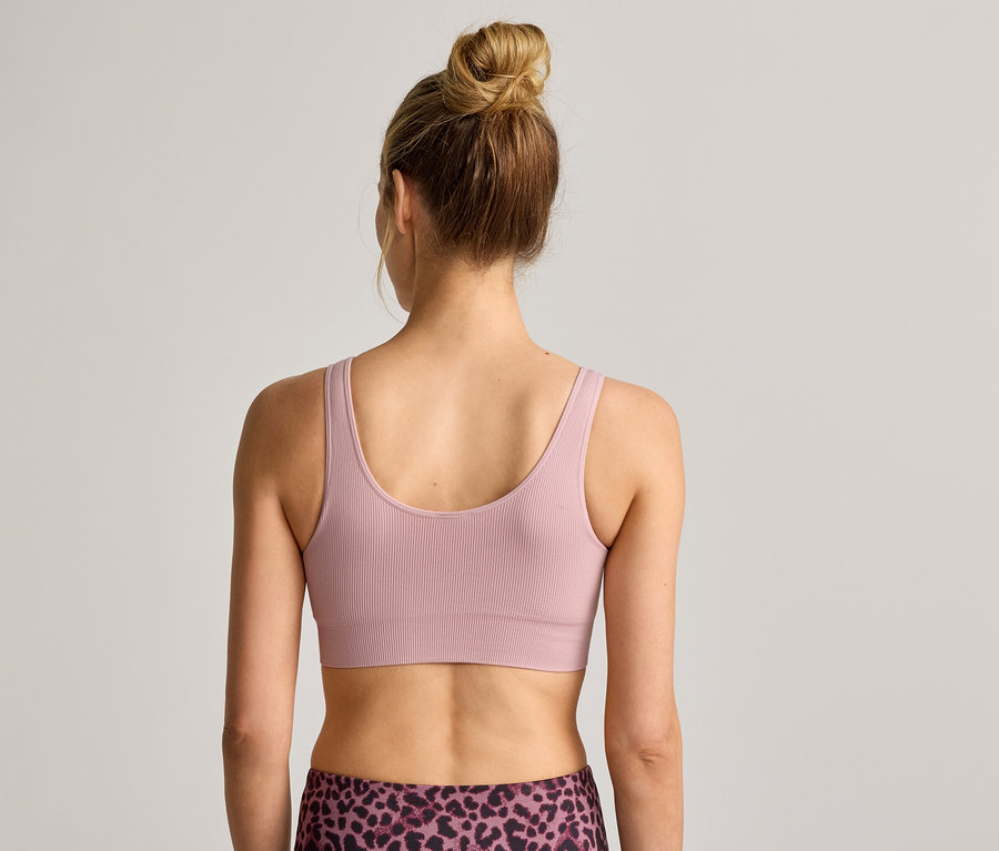 Vue arrière d'une femme portant un chignon, une brassière de sport côtelée et un legging à motif léopard.