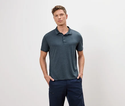 Un homme portant un polo bleu et un short bleu se tient devant un fond blanc.