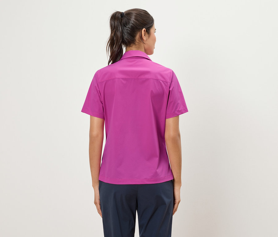 Vue arrière d'une femme avec une queue de cheval portant une chemise rose et un pantalon bleu marine.
