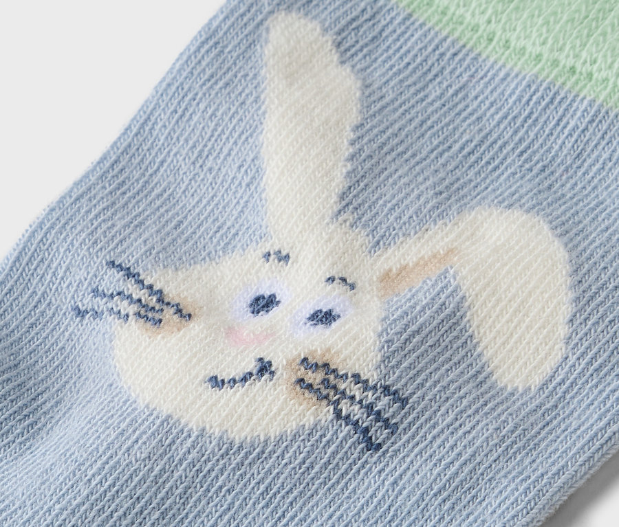 Gros plan d'une chaussette bleu clair avec un motif de lapin brodé.