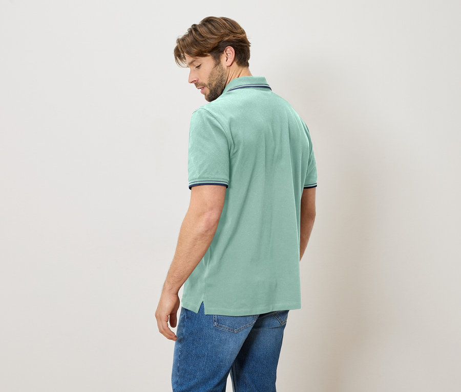 Homme vu de dos, portant un polo bleu clair avec un jean.