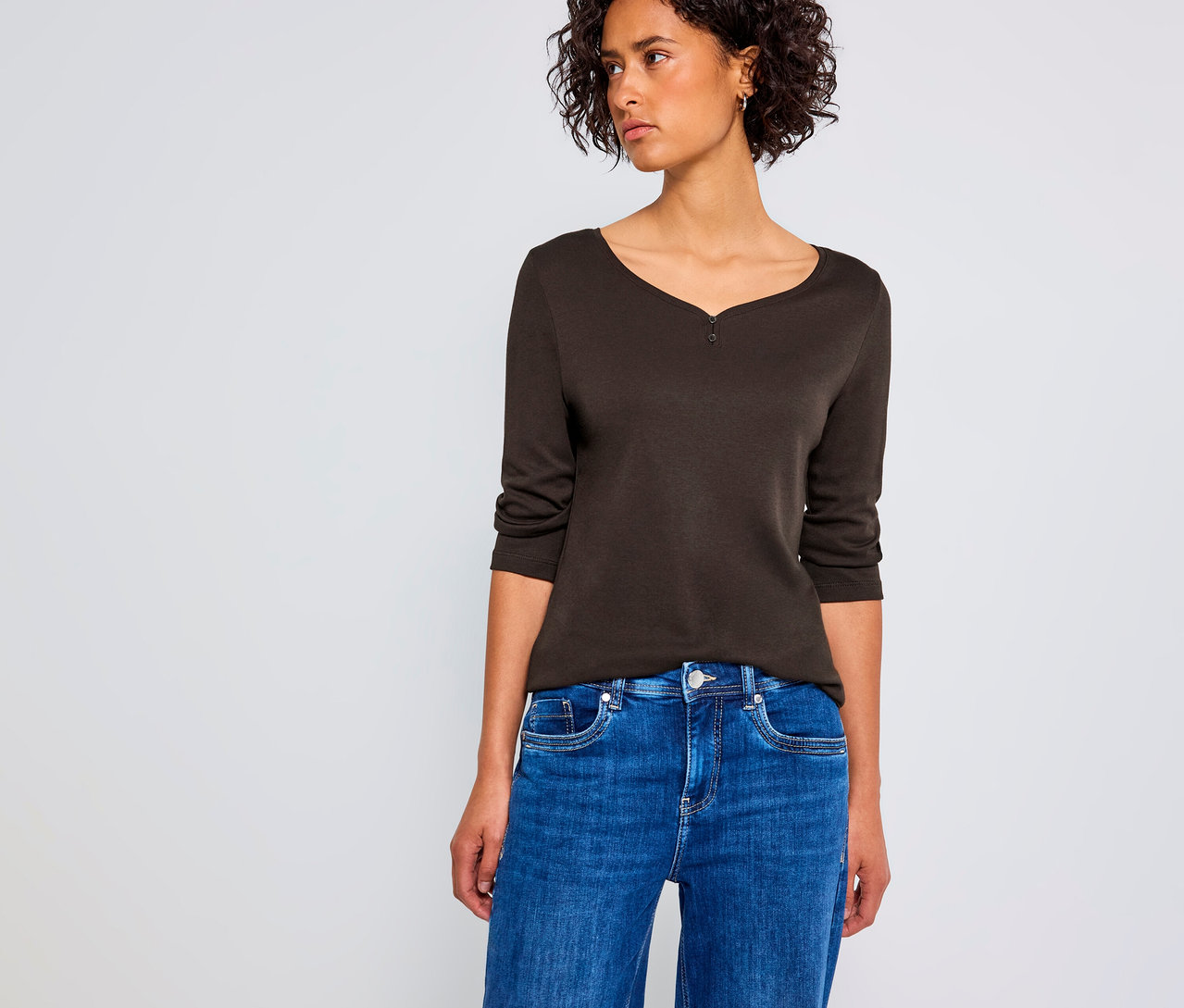 Femme portant un maillot 3/4 avec détail bouton Street One marron et un jean bleu.