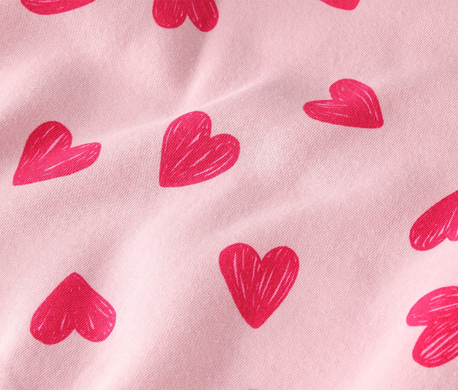 Gros plan d'un tissu rose clair avec un motif de coeurs rouges.
