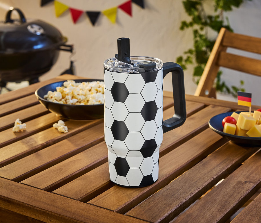 Une tasse de football est posée sur une table en bois à côté d'un bol de pop-corn et de dés de fromage avec des drapeaux allemands et espagnols.