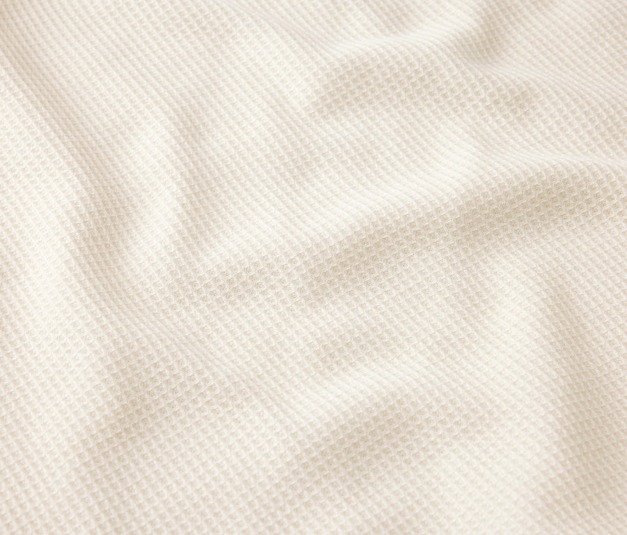 Gros plan d'un tissu gaufré crème avec des plis.