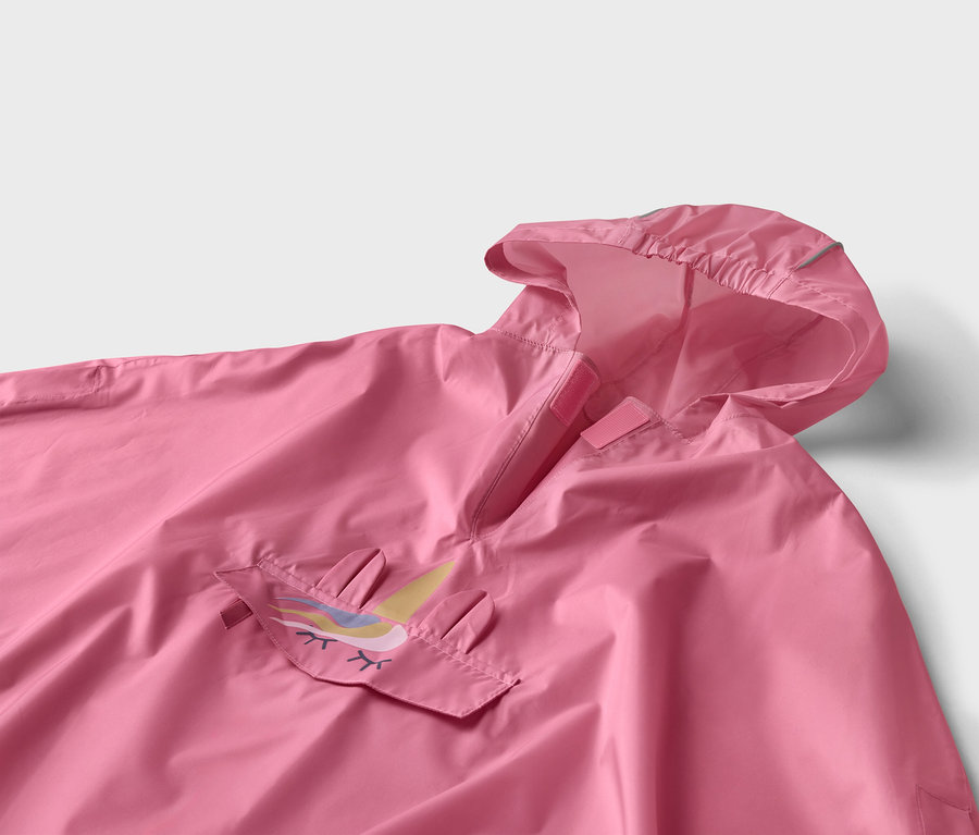 Gros plan d'un poncho rose à capuche avec un appliqué de licorne sur la poche.
