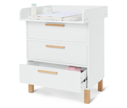 Table à langer blanche avec trois tiroirs, couches, crème et matelas à langer.