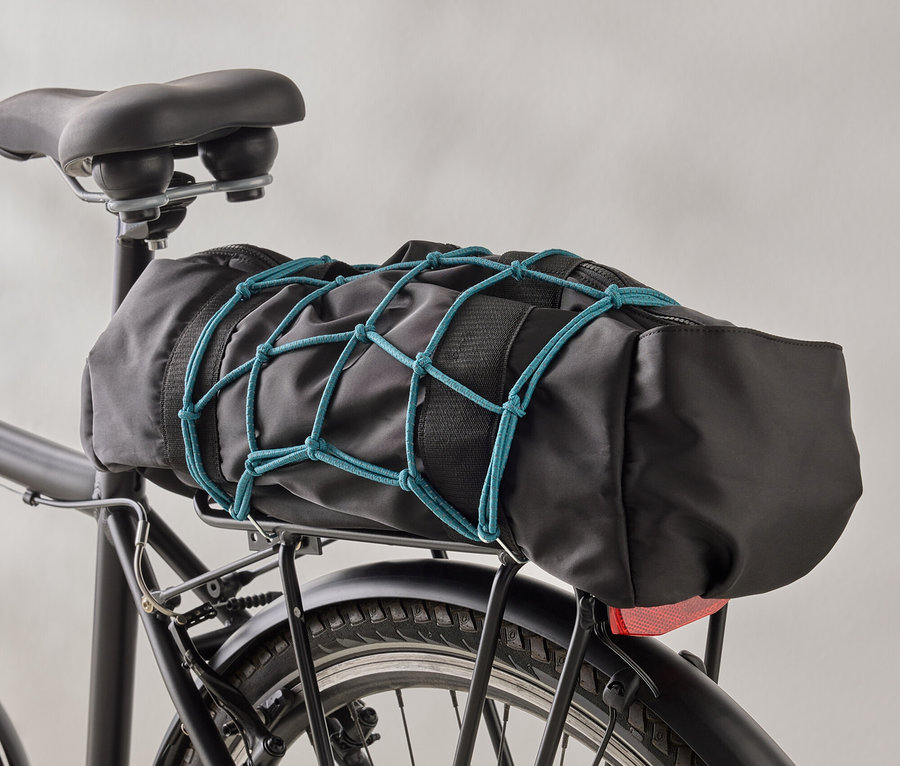 Un sac de vélo noir est fixé à un porte-bagages de vélo noir à l'aide d'un filet à bagages bleu.