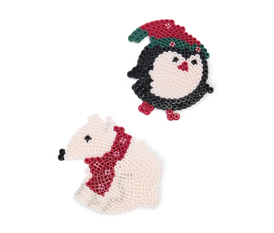 Deux figurines de Noël en perles à repasser : un pingouin noir et blanc portant un bonnet rouge et vert, et un ours polaire blanc avec une écharpe rouge.