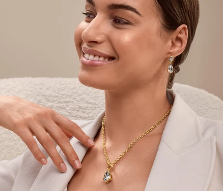 Une femme est assise et porte un collier et des boucles d'oreilles en or.