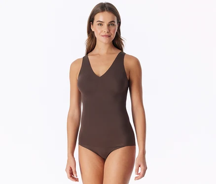 Femme aux cheveux bruns debout, portant un débardeur marron à col en V et un slip assorti, regardant devant elle.