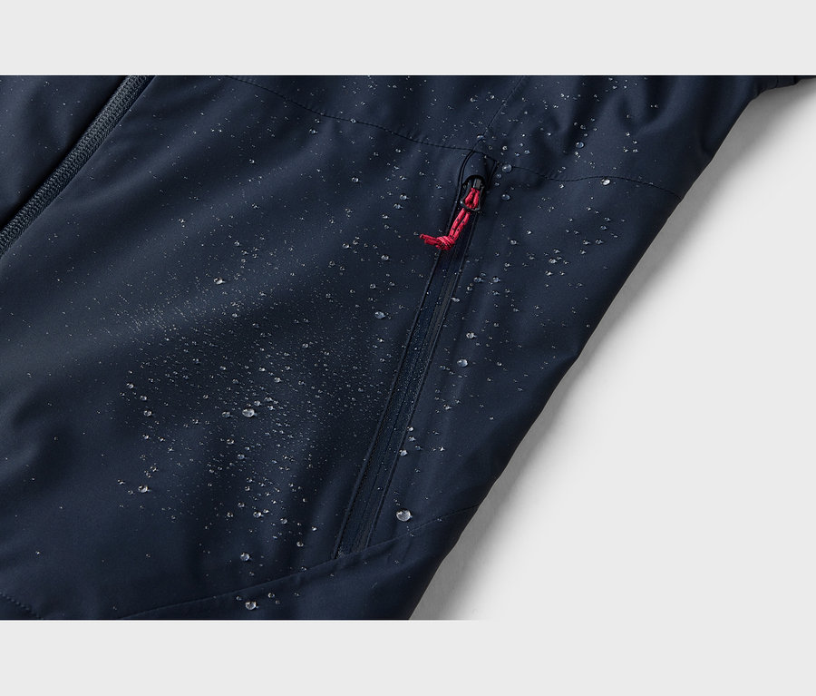 Tissu bleu foncé déperlant avec de nombreuses gouttelettes d'eau perlantes. Une fermeture éclair avec une tirette rouge est visible.