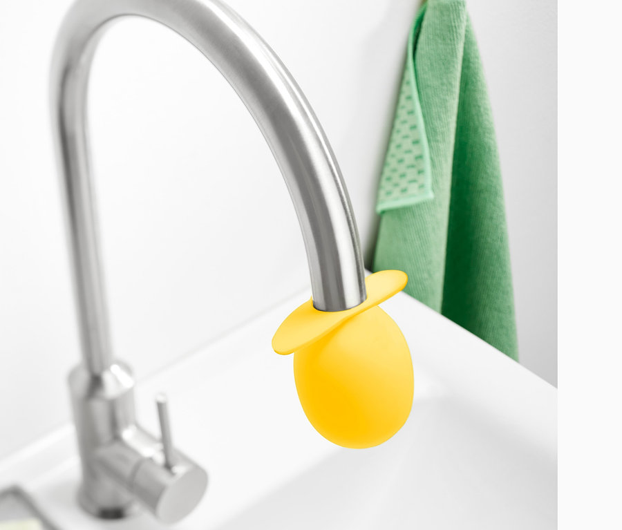 Embout détartrant jaune pour robinet sur un robinet argenté dans un lavabo blanc.