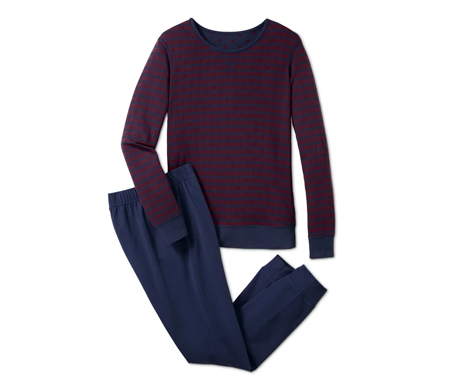 Un pyjama réversible à manches longues est posé, avec un haut rayé et un pantalon bleu.