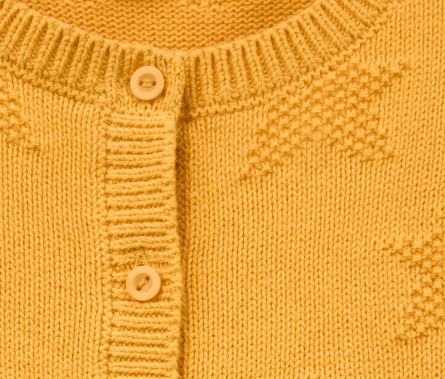 Gros plan sur une jaquette en coton bio jaune avec des boutons.
