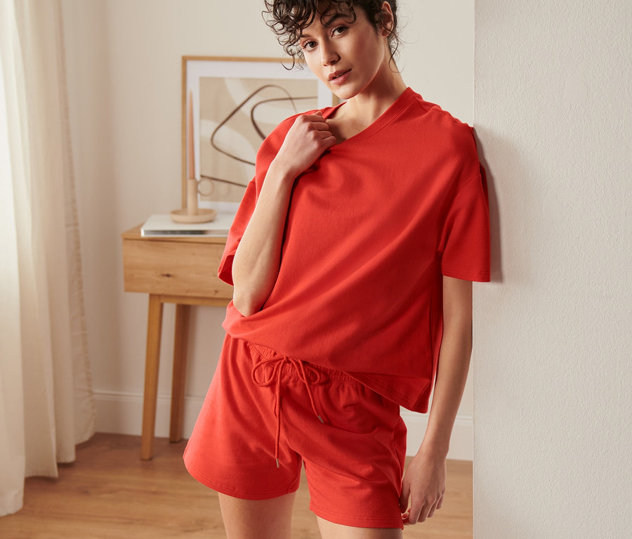 Femme posant en survêtement d’intérieur court orange.