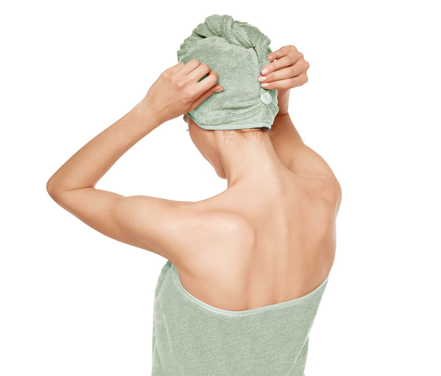 Femme fixant une serviette turban verte.