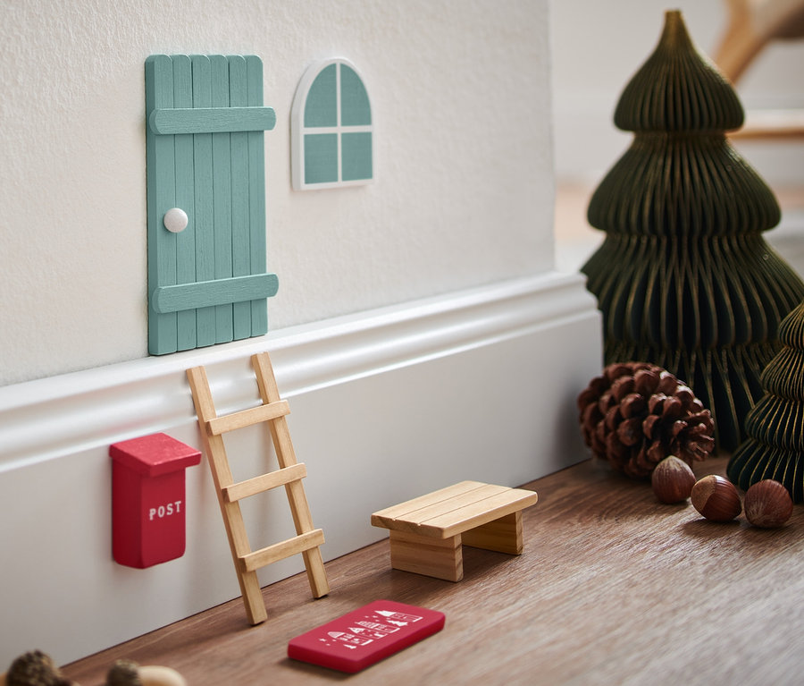 Un kit porte de lutin sur un mur avec des sapins de Noël miniatures et décorations.