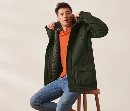 Un homme est assis sur un tabouret et porte une veste.