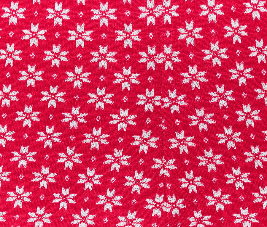 Gros plan sur un legging en maille rouge avec des flocons de neige blancs.