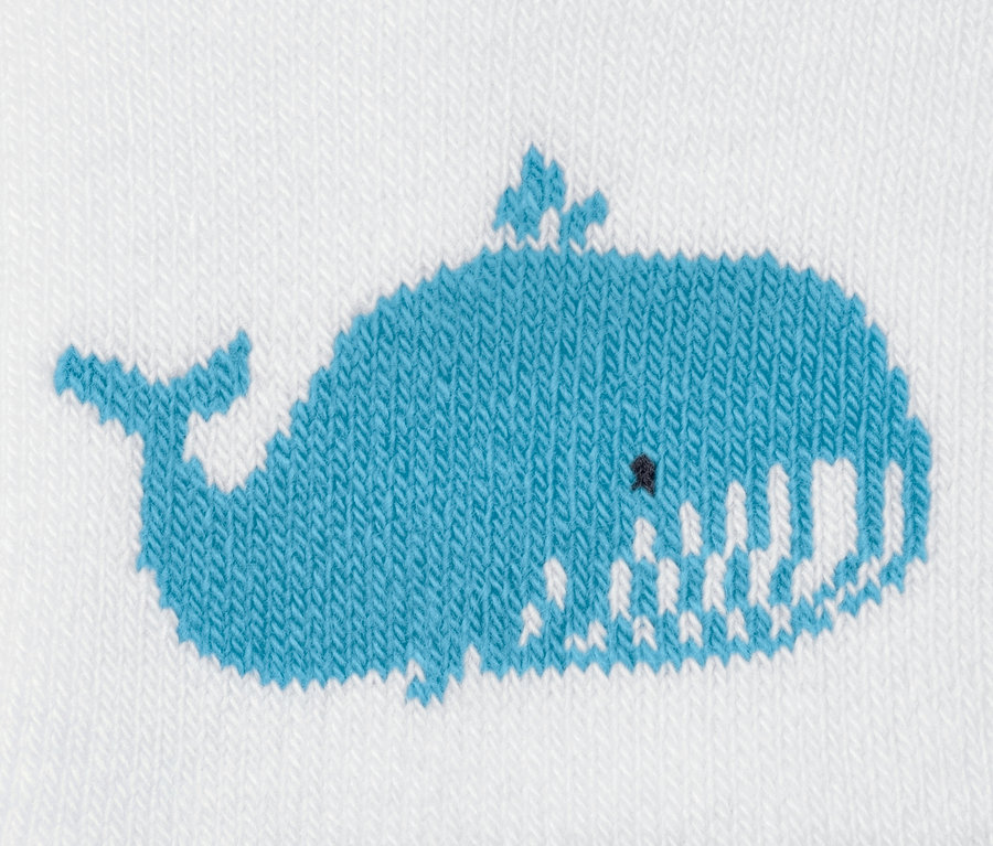 Détail d'une petite chaussette en éponge pour bébés avec un motif de baleine bleue.