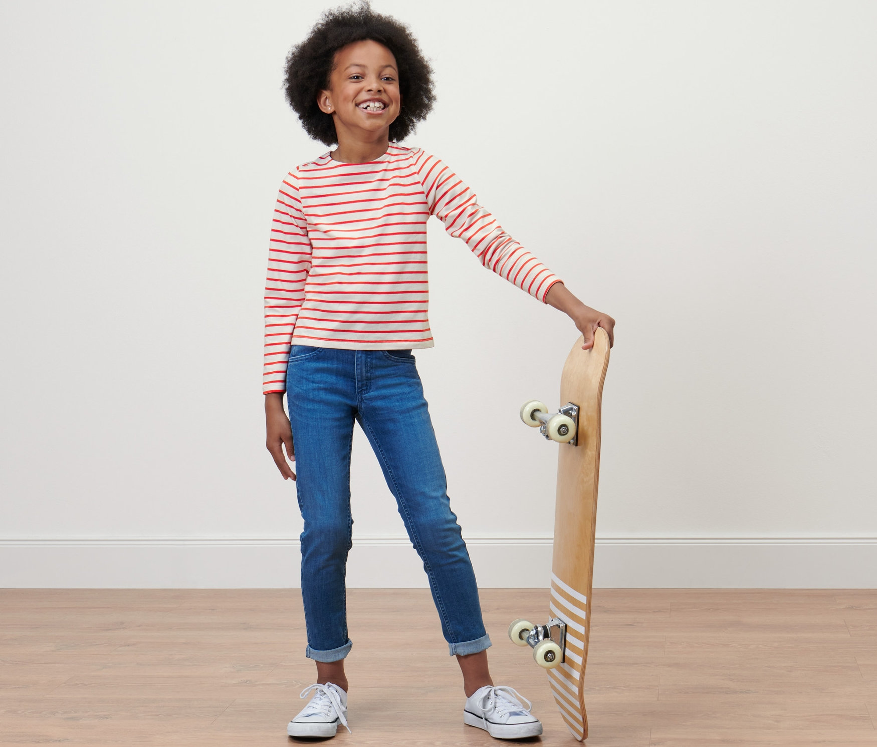 Fille posant avec un skateboard et portant un t-shirt cropped pour enfant.
