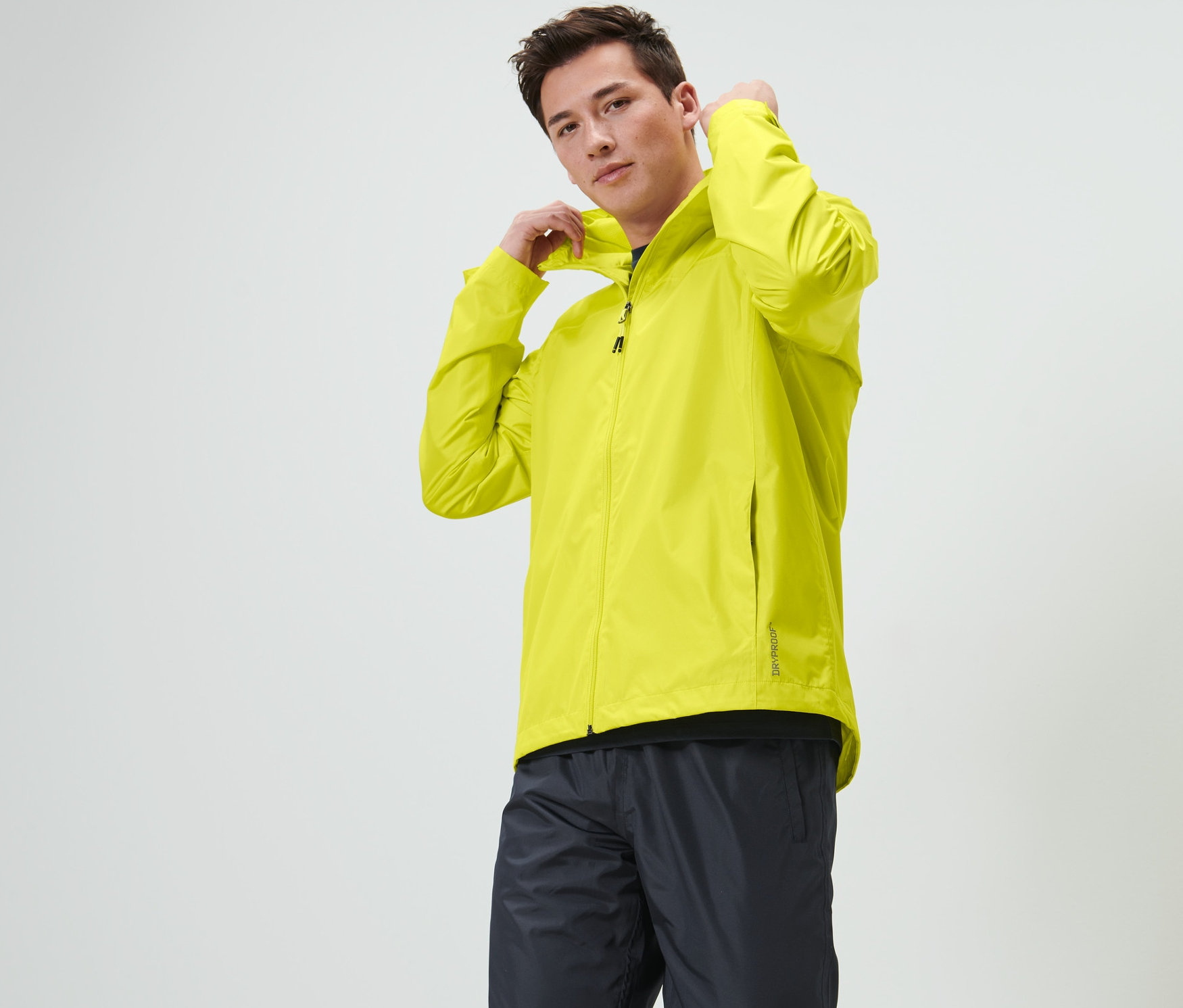 Un homme ajuste la capuche d'une veste de pluie unisexe, vert citron.