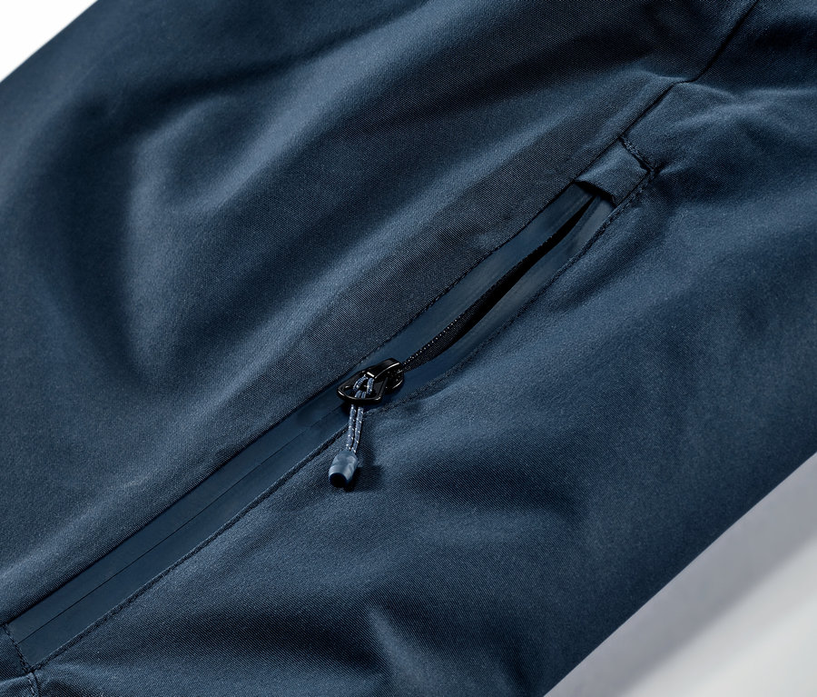 Gros plan sur un pantalon de ski et de snowboard bleu marine avec une poche zippée.