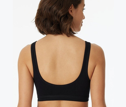 Vue arrière d'une femme aux cheveux bruns courts portant une brassière noire SCHIESSER à bonnets en coton bio.