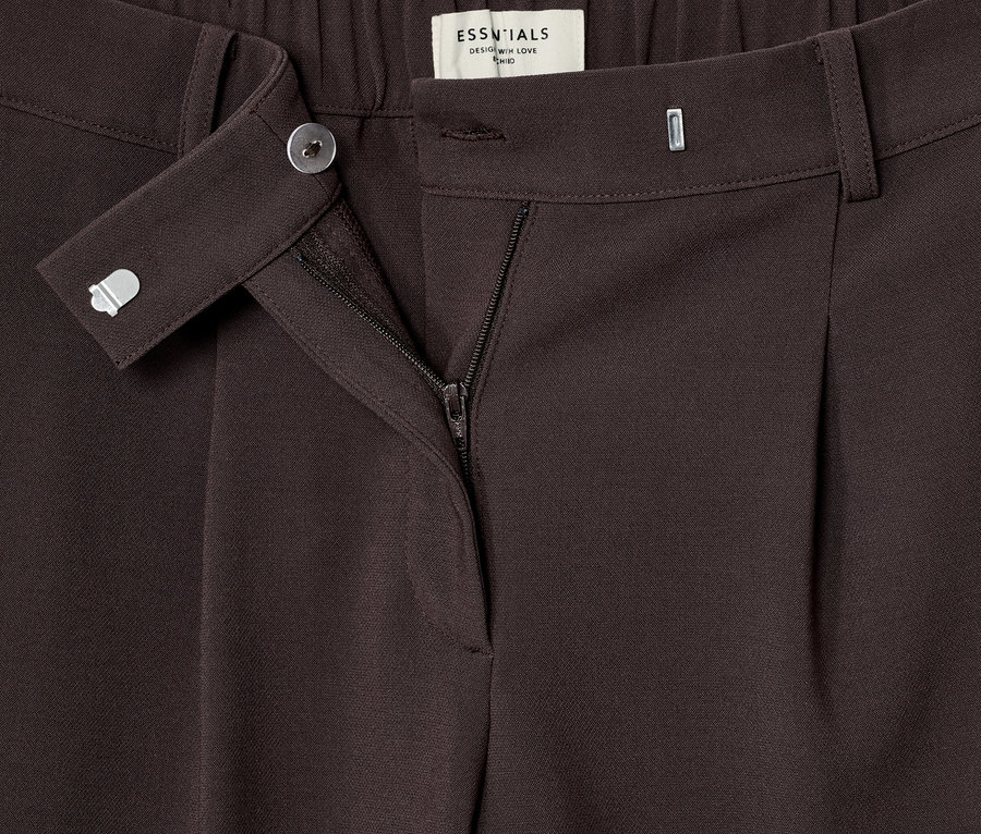 Gros plan sur un pantalon tissé à pinces marron.