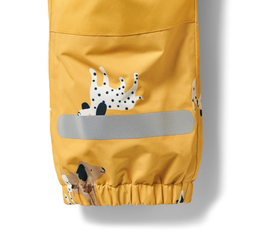 Détail d'une combinaison de pluie jaune avec motif de chiens et bande réfléchissante.
