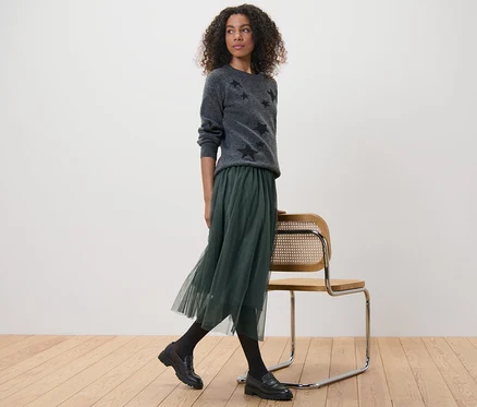 Femme portant un pull gris à étoiles et une jupe en tulle.