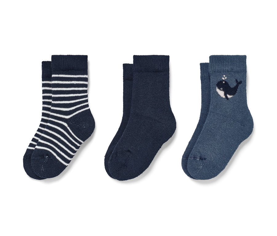 Trois paires de chaussettes pour bébé : une paire rayée, une paire bleu marine, une paire avec une baleine.