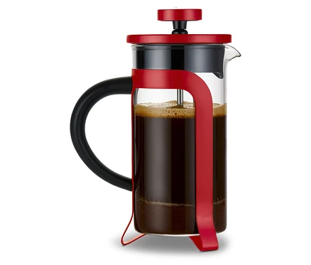 Une cafetière à piston rouge de 300 ml avec 2 tasses remplie de café. Un set cadeau « Amour-To-Go » est visible en arrière-plan.