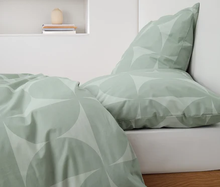 Parure de lit verte en renforcé avec motif géométrique sur un lit.