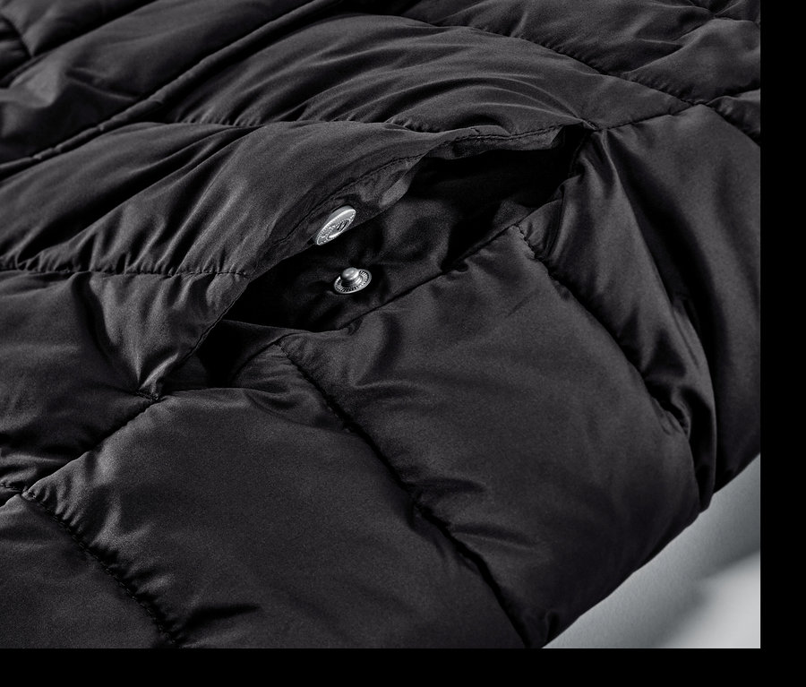 Gros plan sur un manteau matelassé noir à capuche avec des boutons-pression.