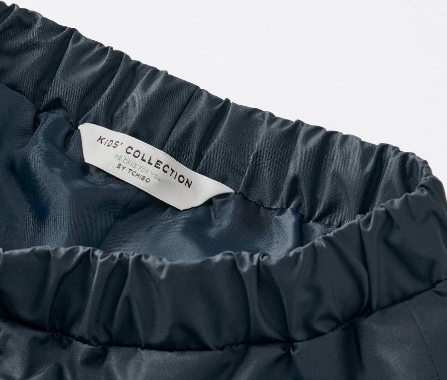 Gros plan sur un pantalon de pluie pour enfant bleu foncé avec taille élastique et étiquette Kids' Collection.