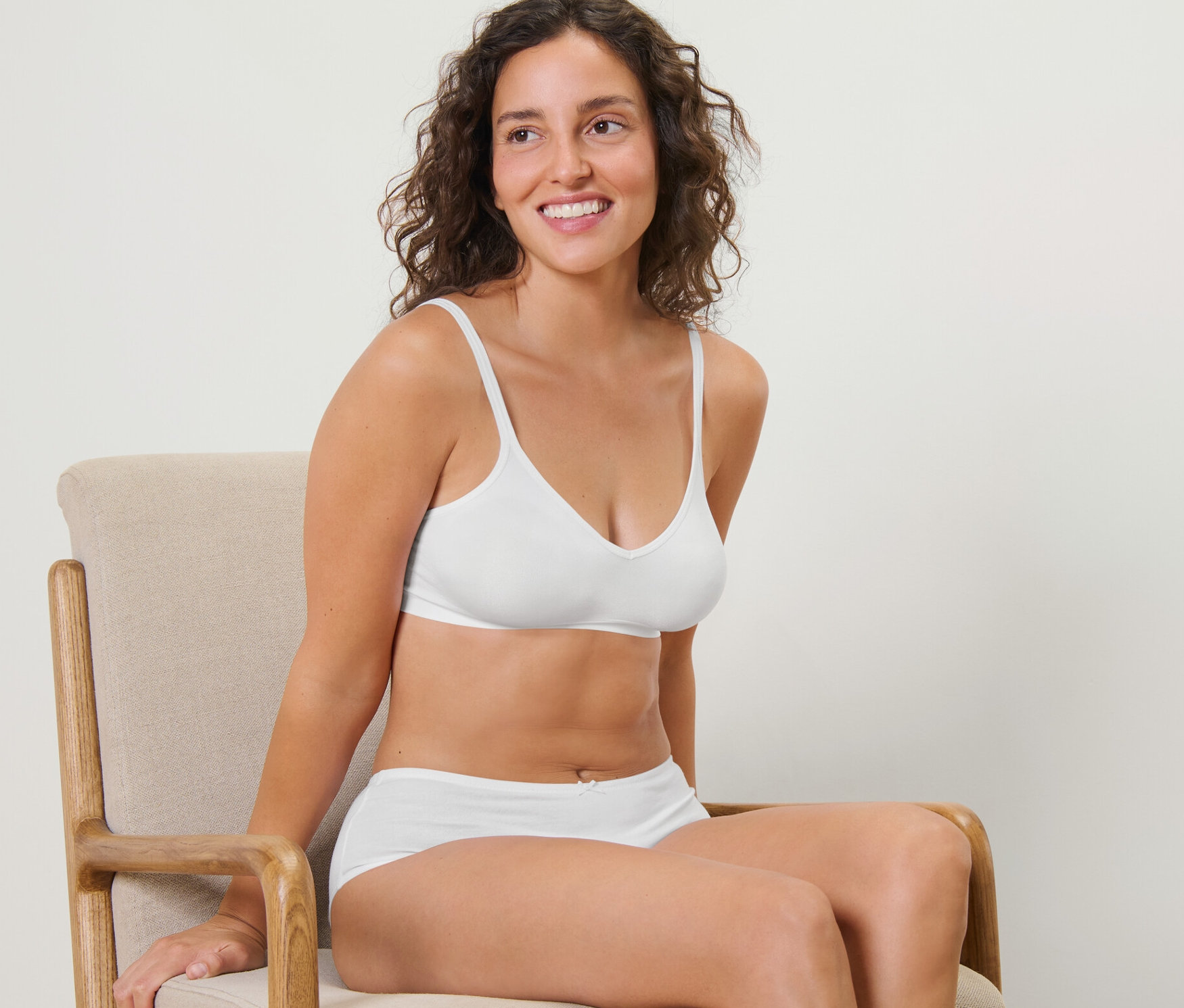 Une femme est assise sur une chaise et porte un soutien-gorge doux Seamless blanc.