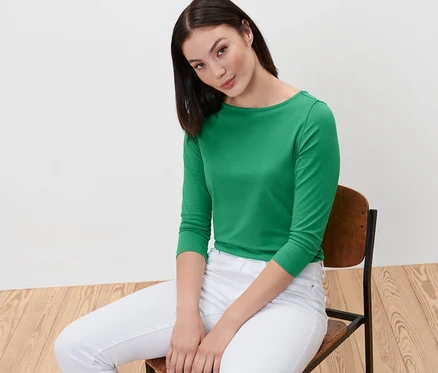 Femme assise sur une chaise portant un t-shirt vert à manches 3/4.