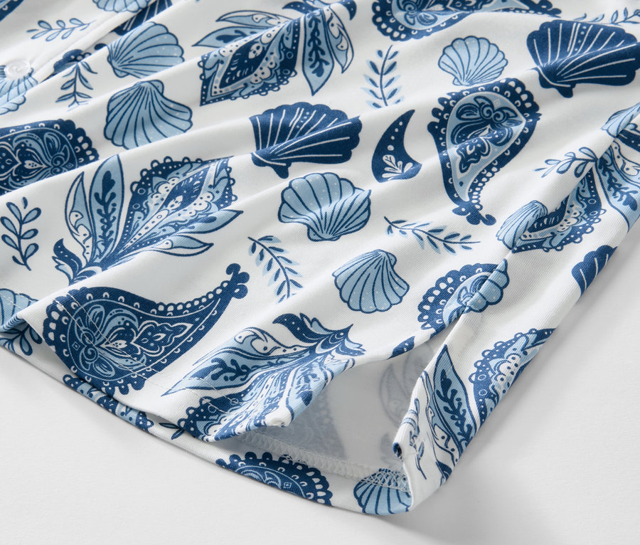 Gros plan sur une chemise de nuit à motifs bleus de coquillages et de cachemire sur fond blanc.