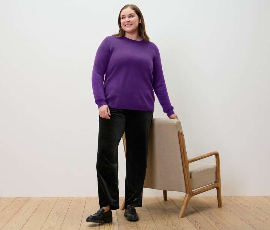 Femme posant en pull violet en maille fine avec du cachemire et pantalon palazzo noir en velours.