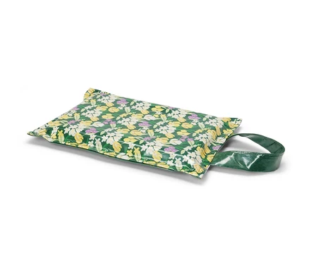 Coussin pour genoux à fleurs avec une poignée verte.