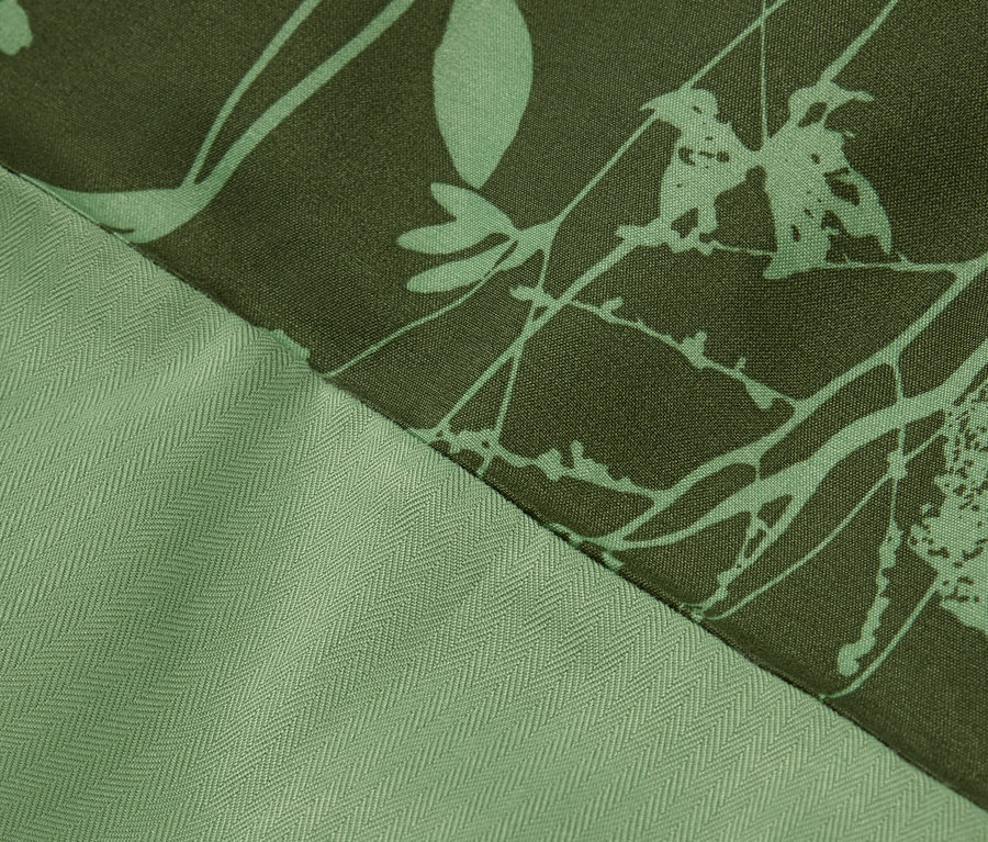 Gros plan d'un tissu vert avec un motif floral et une texture à chevrons.