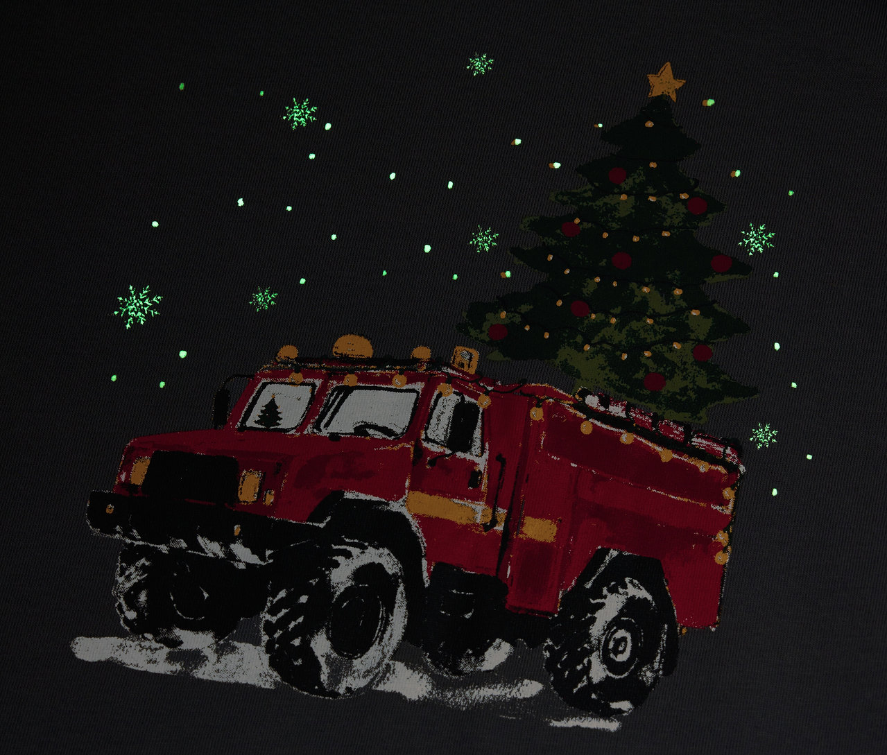 Un camion de pompiers rouge transporte un arbre de Noël sous la neige.