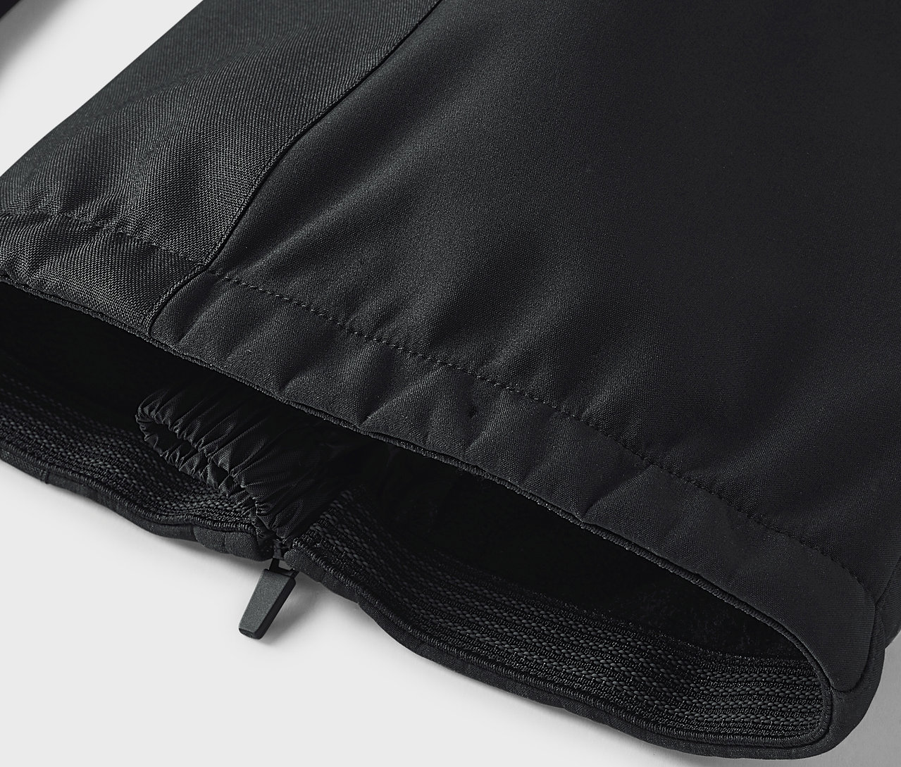 Détail d'un pantalon noir avec fermeture éclair et ourlet élastique.