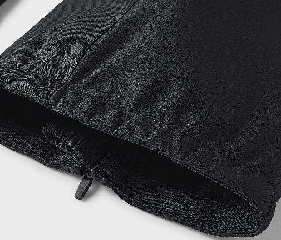 Détail d'un pantalon noir avec fermeture éclair et ourlet élastique.