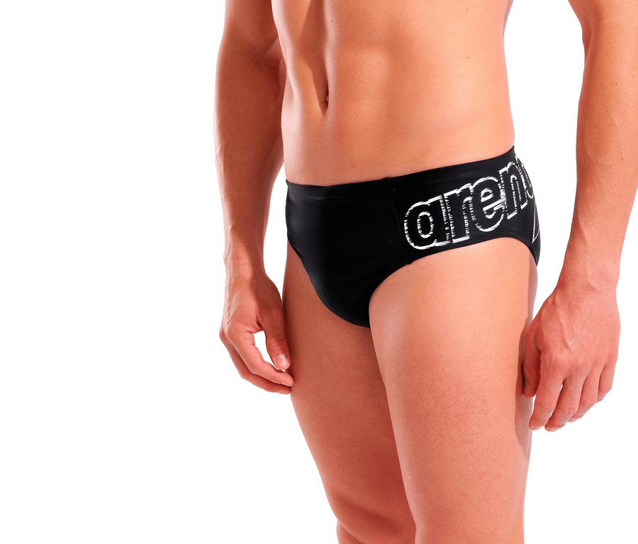 Un homme pose en maillot de bain slip arena Scratchy, noir.